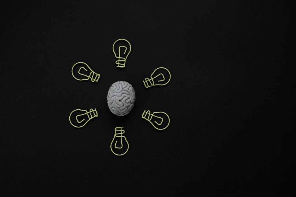 Conceptual photo of a brain surrounded by light bulb clips on black background.