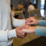 Mid-section of couple holding hands in waiting area at airport terminal